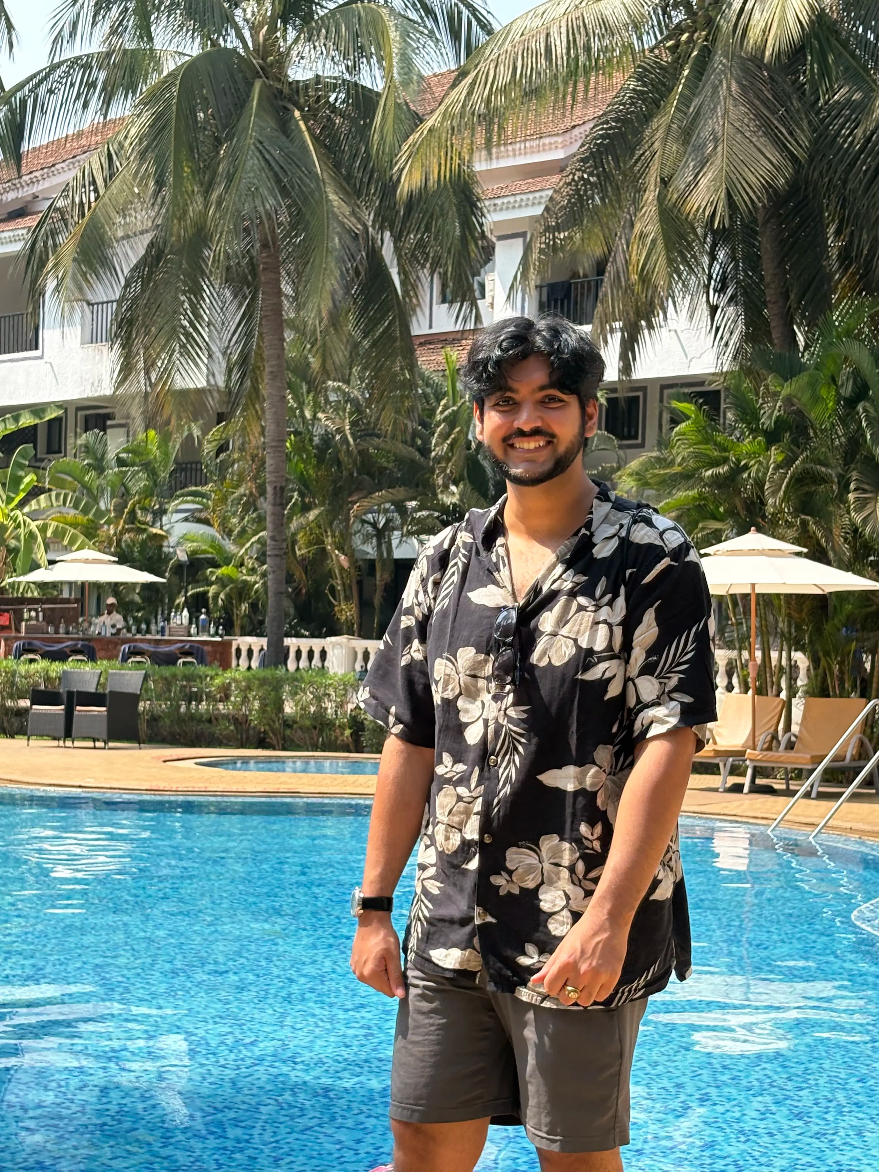 Portrait of Anadi Mishra by a pool in a floral shirt